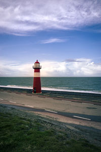 Lighthouse by sea against sky