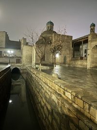 Buildings by canal against clear sky in city