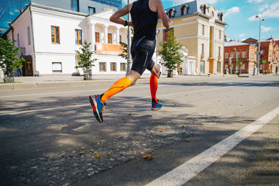 Runner athlete in compression socks running marathon on city street	
