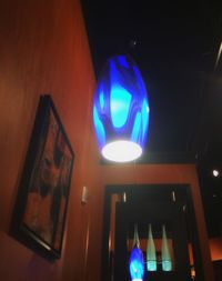 Low angle view of illuminated lighting equipment hanging on wall