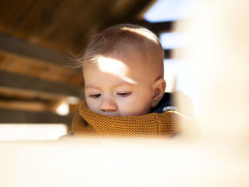 Close-up of cute girl wearing sweater sitting at home