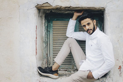 Young man sitting on wall