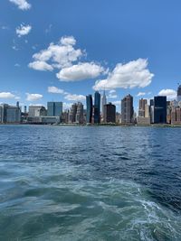 Sea by buildings in city against sky