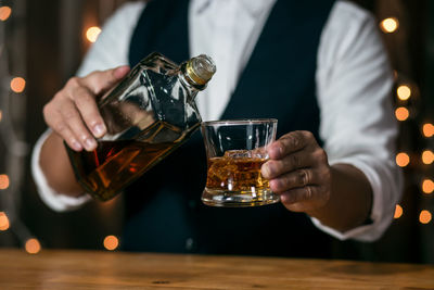 Midsection of man pouring wine in glass