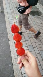 Low section of man holding ice cream cone on sidewalk