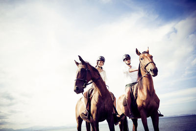 People riding horses on street against sky