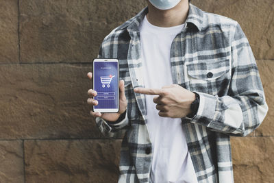 Midsection of man showing mobile phone