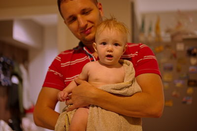 Little baby girl in towel after bath held by her father