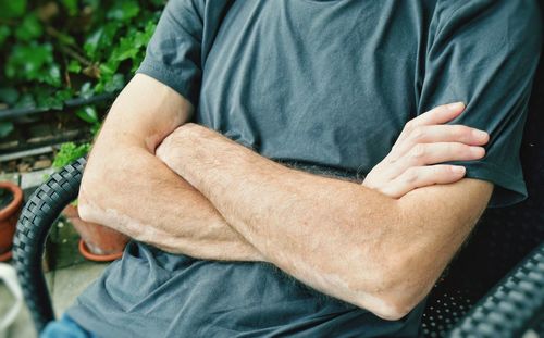 Midsection of man with arms crossed