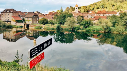 Houses by lake and buildings against sky