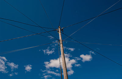 Low angle view of electricity pylon against blue sky