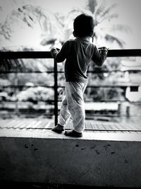 Rear view of boy standing by railing