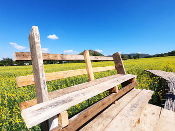 Wooden fence on field against blue sky