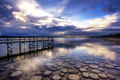 Pier over sea against sky during sunset