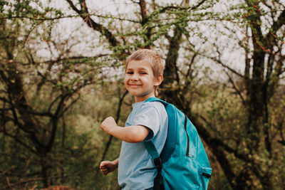 Happy boy standing against trees