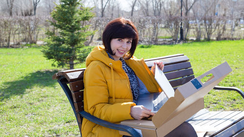 Young woman using mobile phone while sitting on field