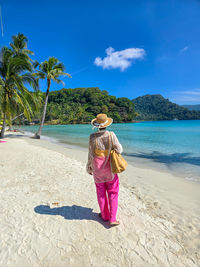 Rear view of woman standing at beach against sky