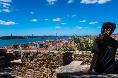 A teenager girl looking the urban landscape of lisbon. the 25th of april bridge in the background. 