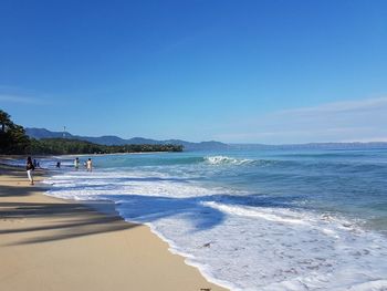 Scenic view of beach against clear blue sky