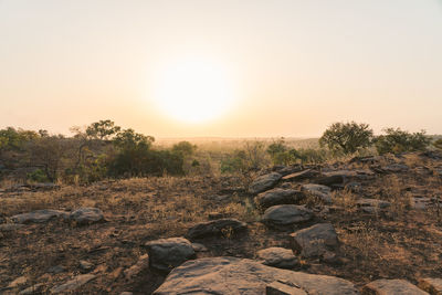 Scenic view of rocks against clear sky during sunset