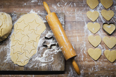 High angle view of cookies and rolling pin with cutter on table