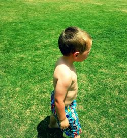 High angle view of shirtless boy standing on field