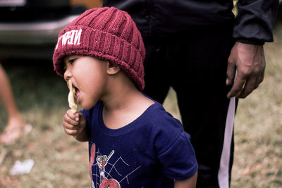 Boy eating ice cream while standing outdoors