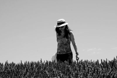 Woman standing by plants in farm against sky