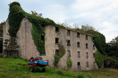 Tractor on field by building against sky