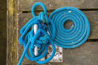 Directly above shot of blue rope tied on cleat at harbor
