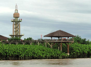 Gazebo and observation point on pier by river against sky