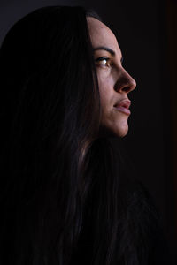 Portrait of young woman against black background