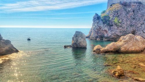 Rock formation in sea against blue sky