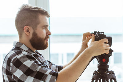 Profile view of man holding camera indoors