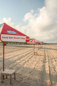 Sign board on beach against sky