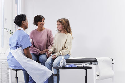 Female doctor talking to girl patient and mother during appointment