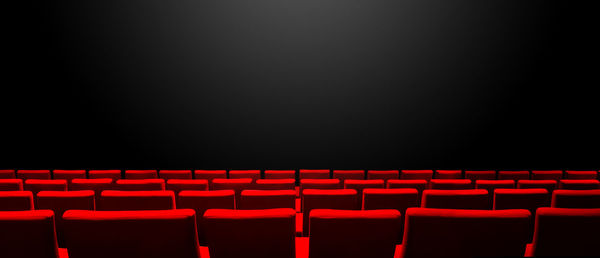 Empty chairs in row against black background