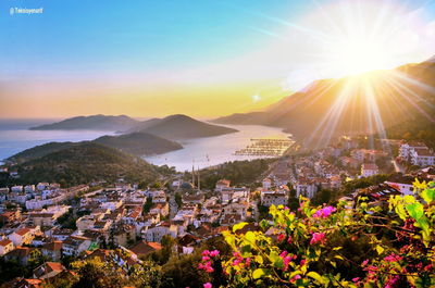 Scenic view of townscape and mountains against sky at sunset