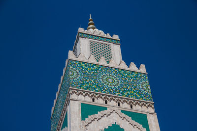 Low angle view of hassan ii mosque tower against blue sky - casablanca, morocco 