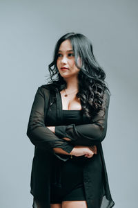 Portrait of young woman standing against white background