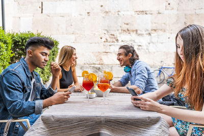 Smiling friends having drinks while sitting at cafe