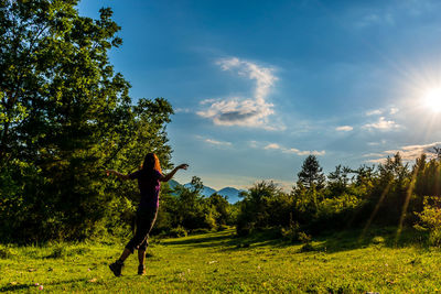 Man standing by tree on field against sky