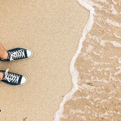 Low section of man standing on beach