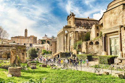 Tourist walking by old ruins at roman forum against sky