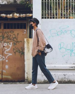 Full length of man standing against graffiti wall