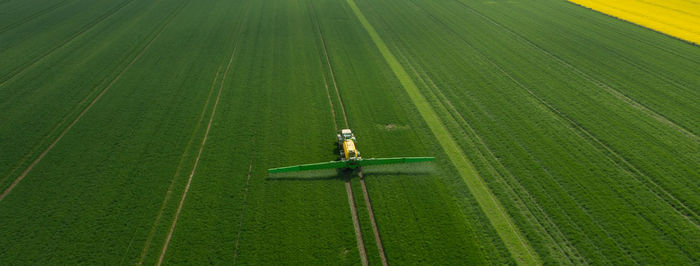 Tractor with field sprayer when applying pesticide against pesticide