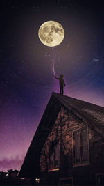 Low angle view of person on roof against moon at night