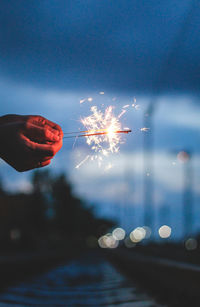 Close-up of hands holding illuminated sparklers at night