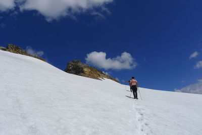 Rear view of people hiking on snow covered field against sky