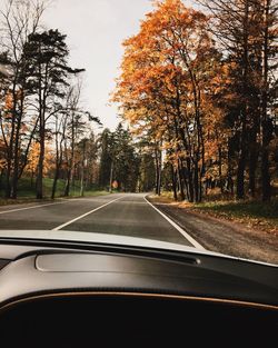 Road amidst trees seen through car windshield